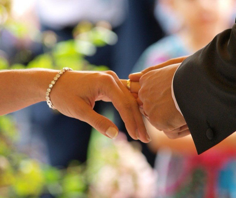 Manos de una pareja colocando un anillo durante una ceremonia