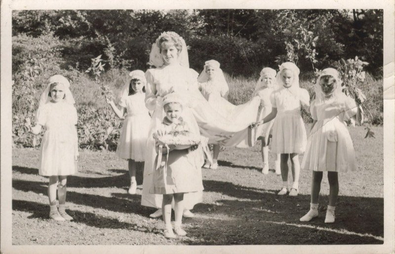Niñas de arras vestidas de blanco sujetando la cola de una novia, fotografía de archivo de los años veinte